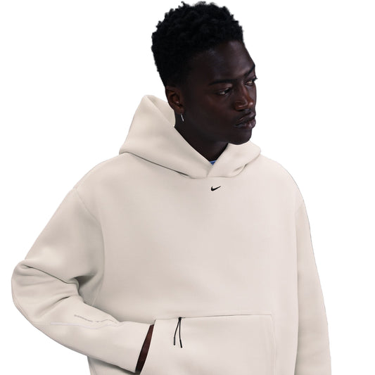 Person wearing a beige hoodie with a Nike logo on a dark background