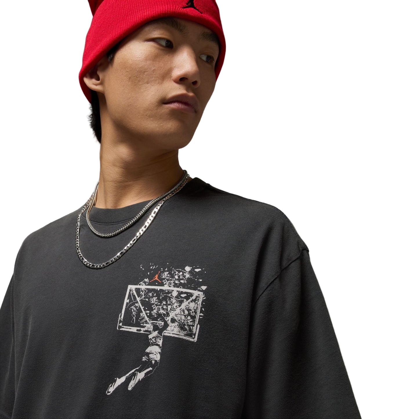 Person wearing a black t-shirt with a graphic design and a red beanie on a gray background