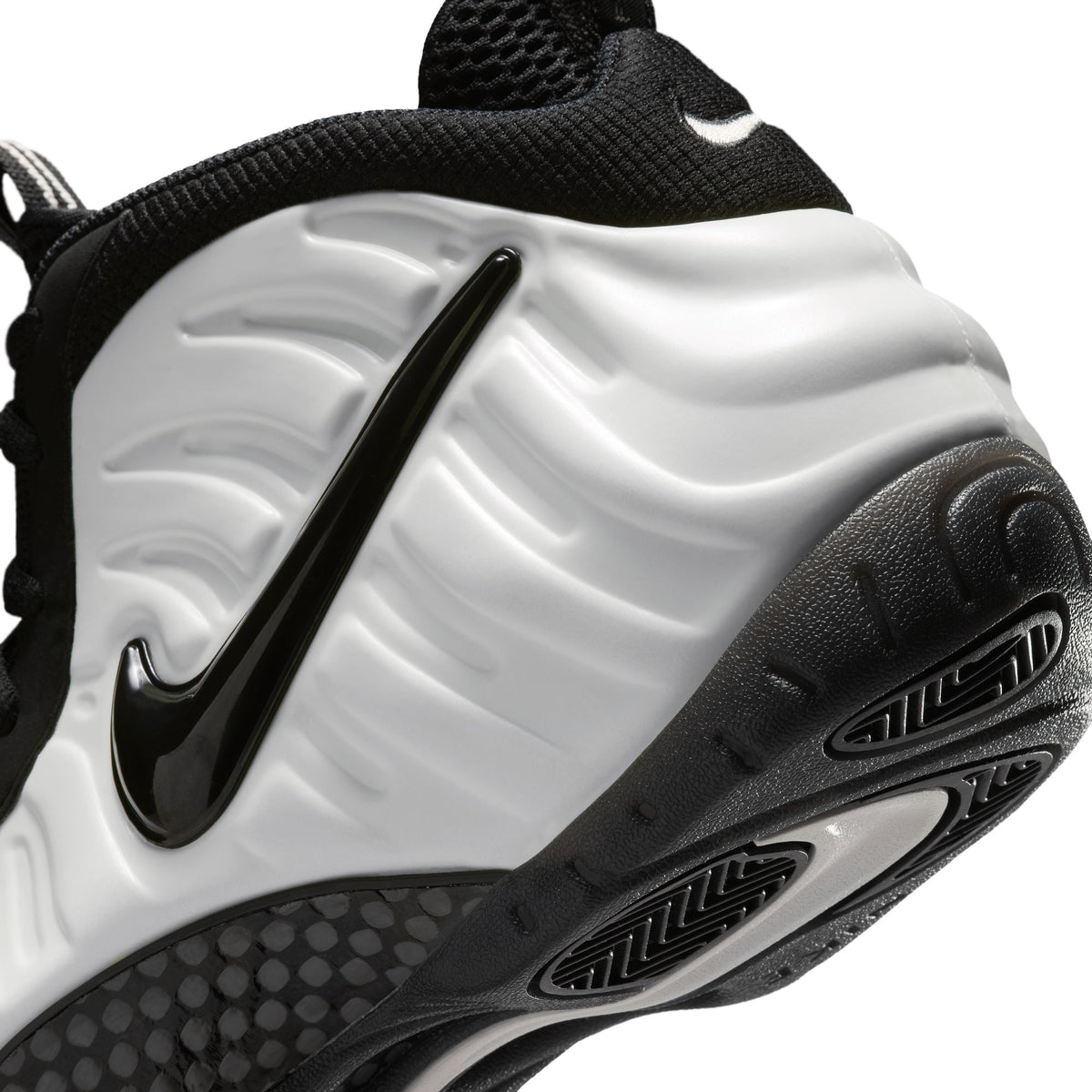 Nike Air Foamposite Pro close-up of Summit White molded shell with glossy black Swoosh and black outsole
