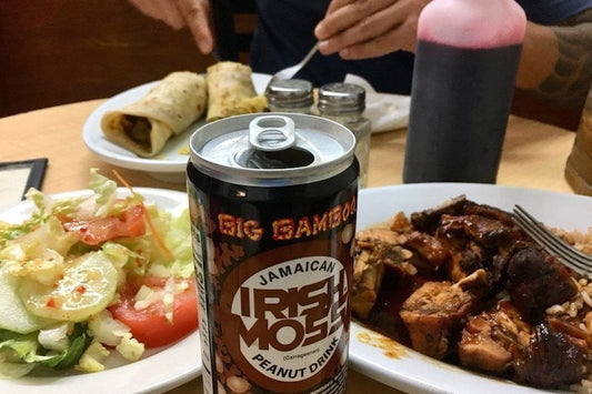Roti wraps, a plate of stewed meat, a side salad and a can of Big Bamboo Irish Moss peanut drink on a table at B&M Market