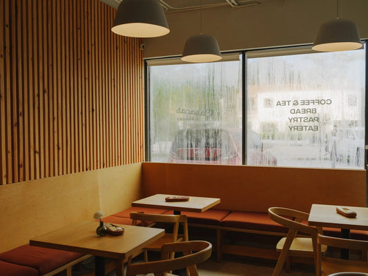 Caracas Bakery MiMo dining room with wood slats, pendant lamps, rust banquettes and a window lettered Coffee & Tea, Bread, Pastry, Eatery