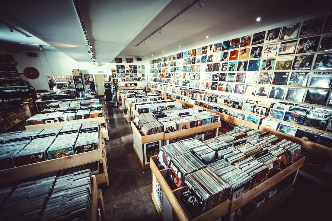 Wide view of Technique Records with rows of wooden vinyl bins and a long wall of album covers under track lighting
