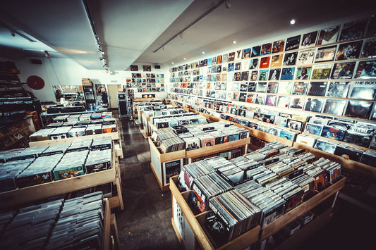 Wide view of Technique Records with rows of wooden vinyl bins and a long wall of album covers under track lighting