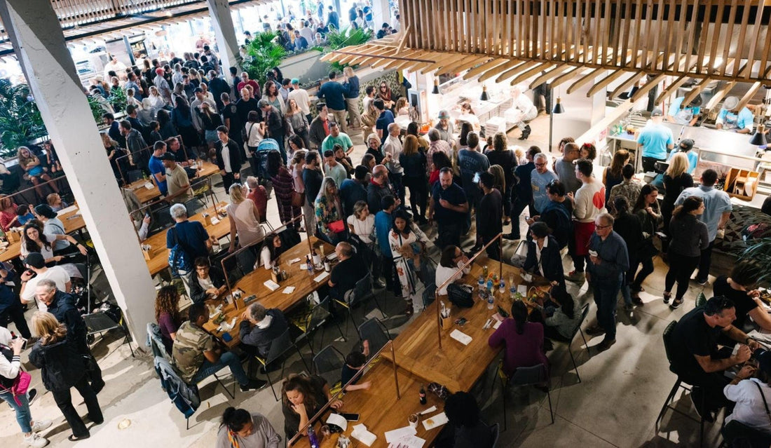 Crowd filling The Citadel food hall, seen from above, with people at long wooden tables and lines at the food counters
