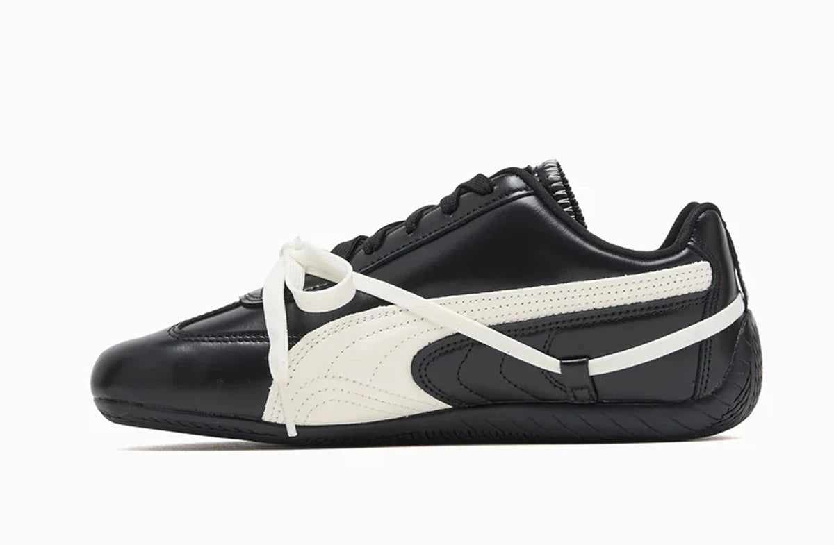 Black and white Puma sneaker with an intricate lacing system and white brand logo on a white background