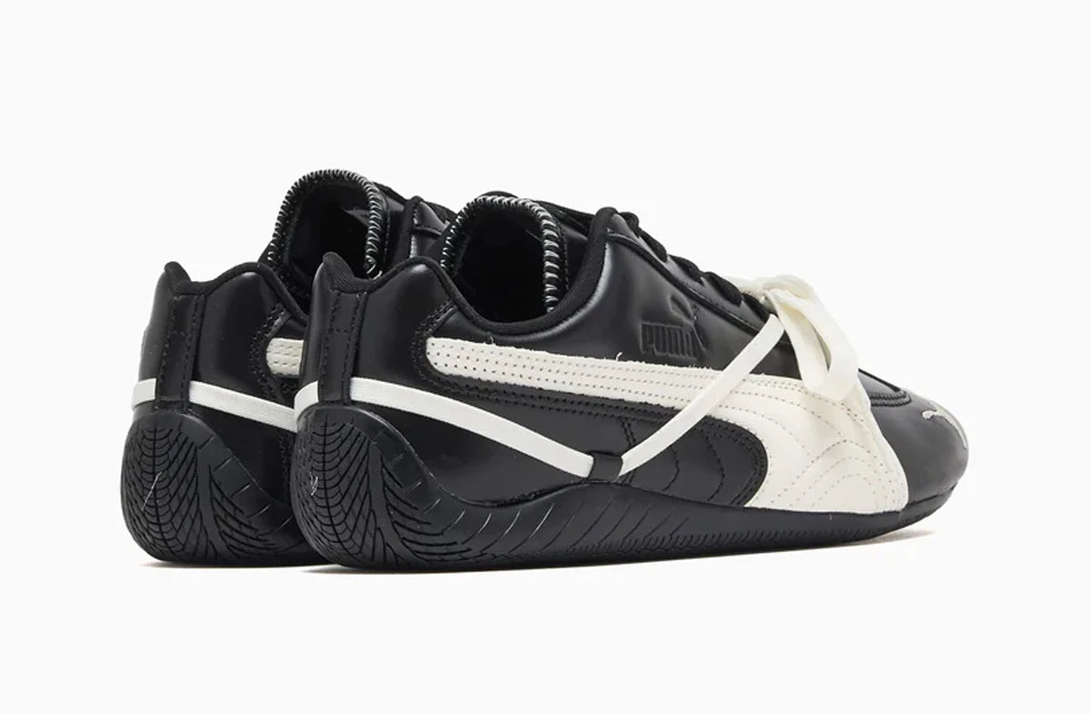 Black and white Puma sneakers with a prominent brand logo on a white background