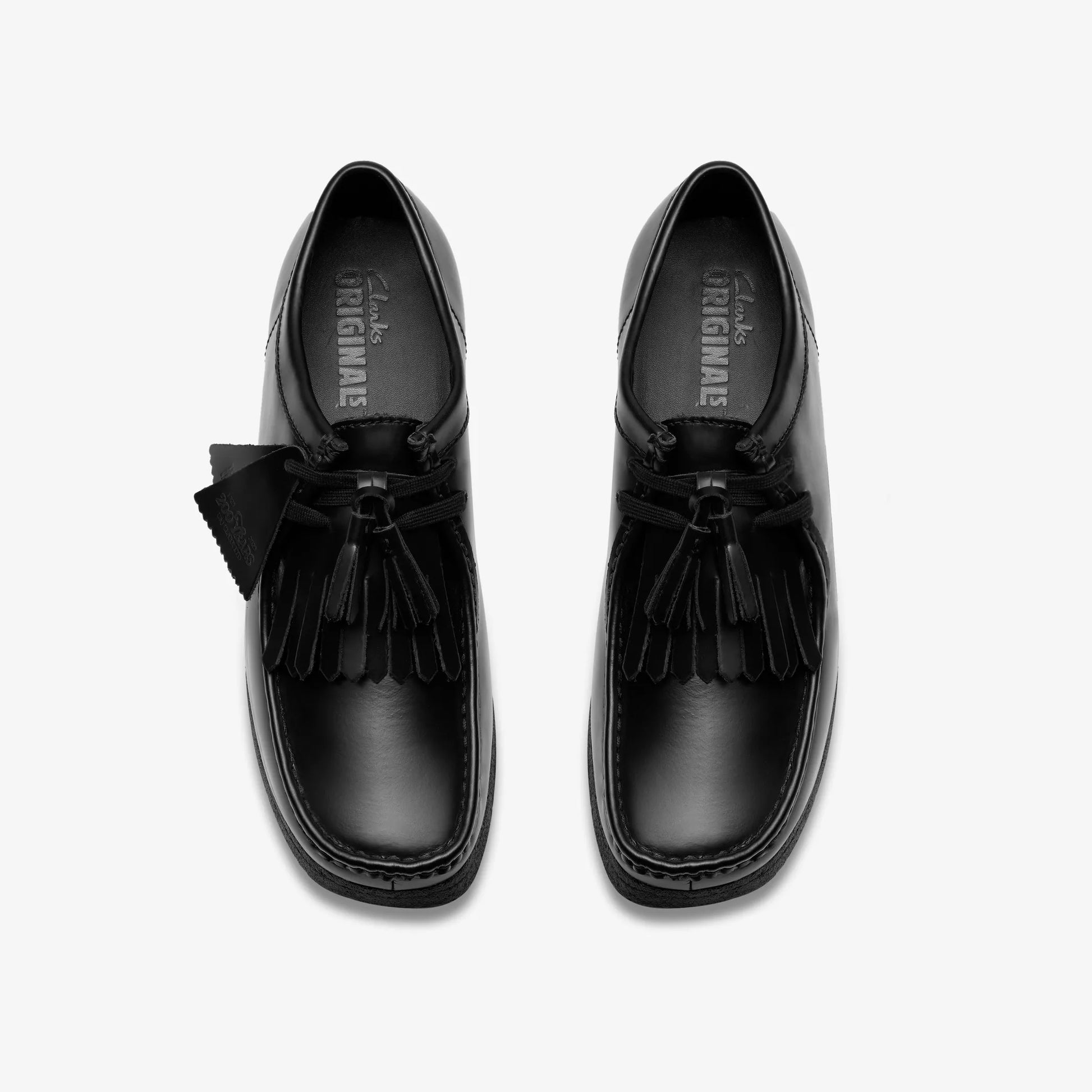 Black loafers with tassels on a white background