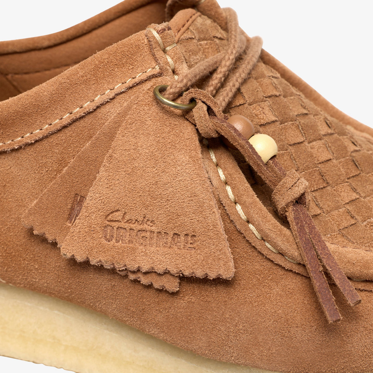 Clarks Wallabee in Tan Weave, close-up of suede tassel with embossed Clarks Originals logo, woven vamp and beads
