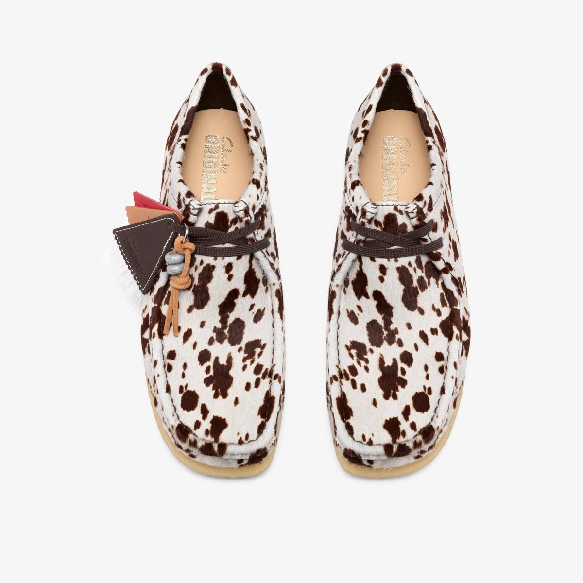 Clarks Wallabee, top view of pair in Brown Cow Print hair, brown laces, leather tag charms and gum soles