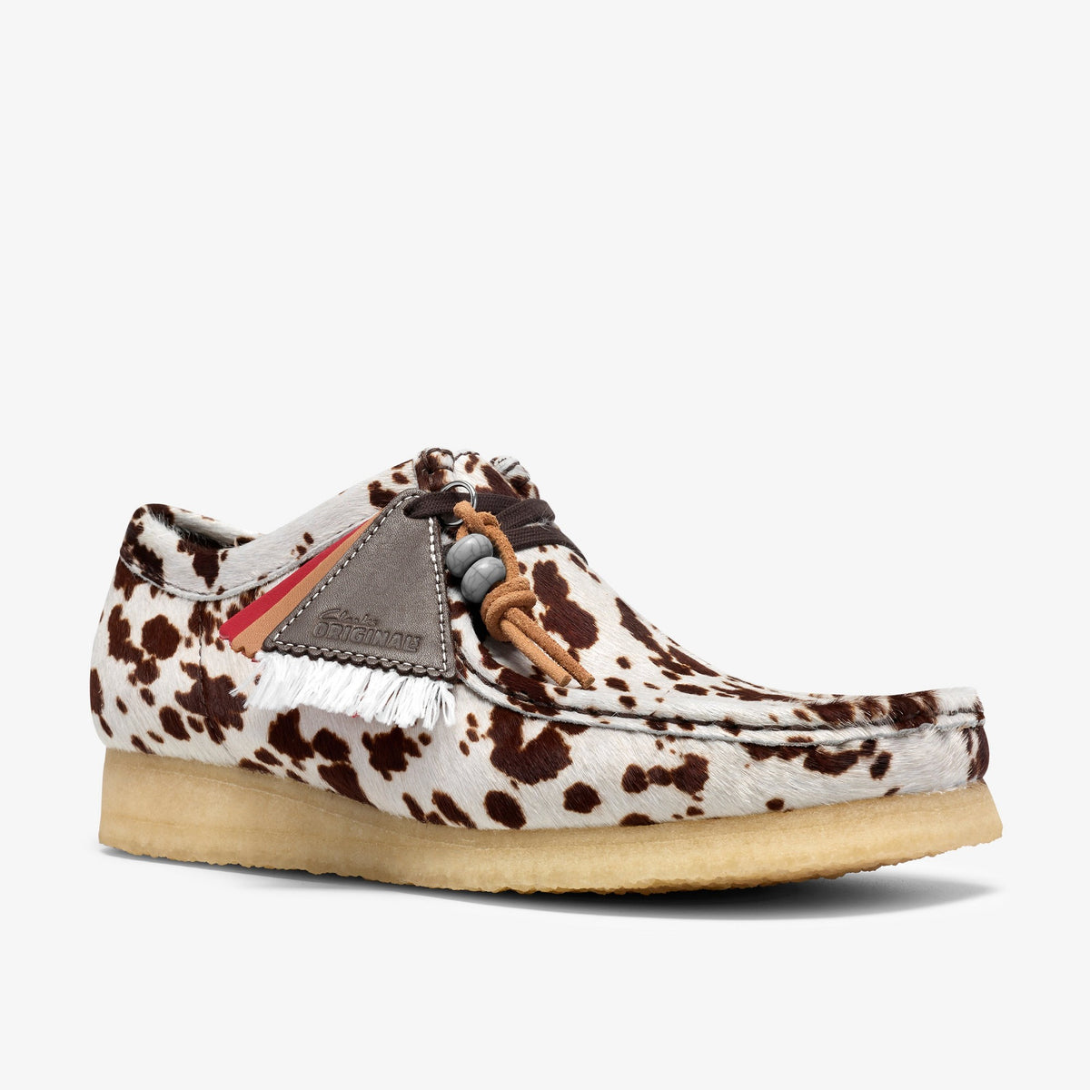Clarks Wallabee three-quarter side view in Brown Cow Print hair, gray suede tag with fringe, beads, crepe sole