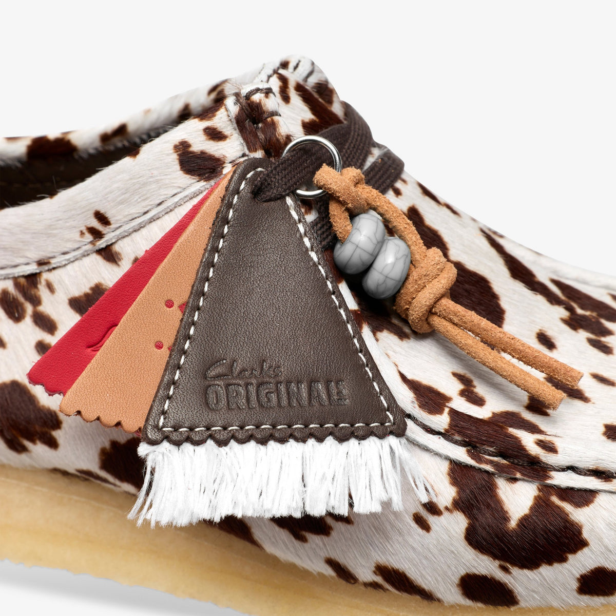 Clarks Wallabee close-up of brown cow print hair upper with Clarks Originals leather tag, fringe, beaded lace