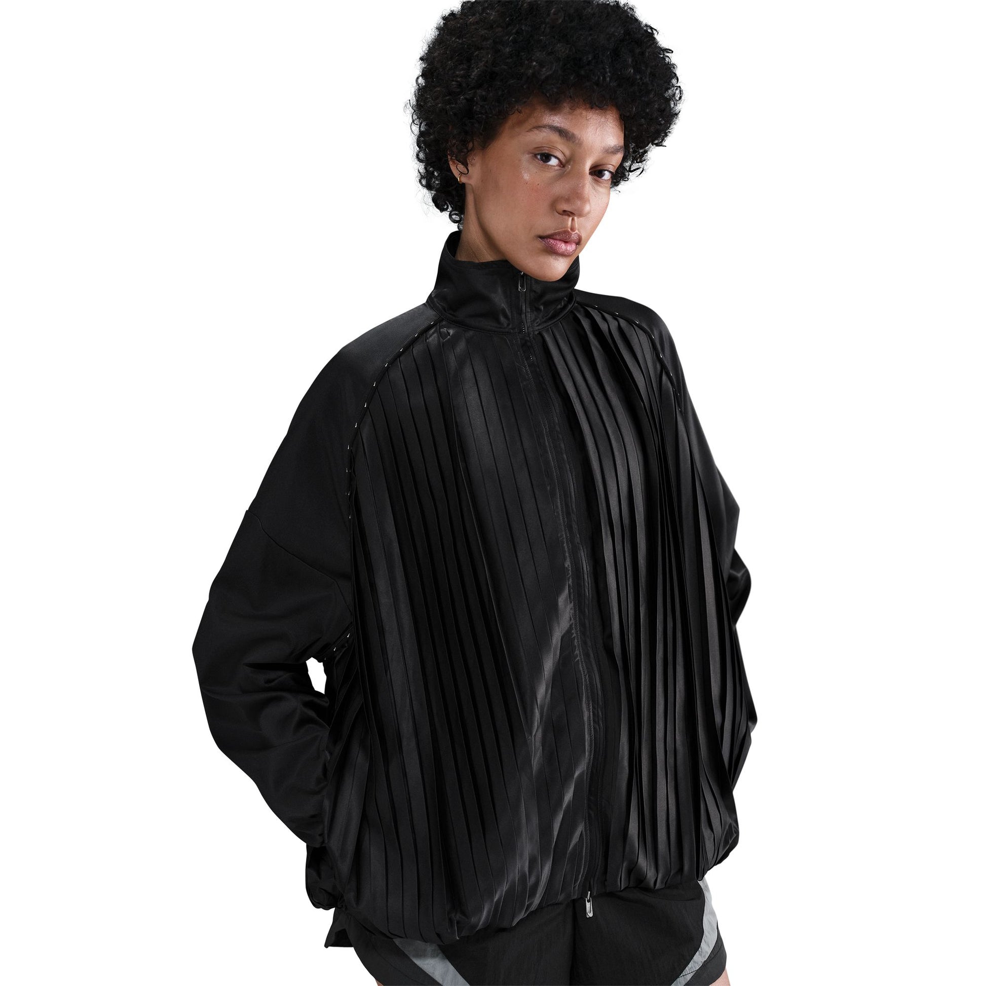 Person wearing a black pleated jacket on a white background
