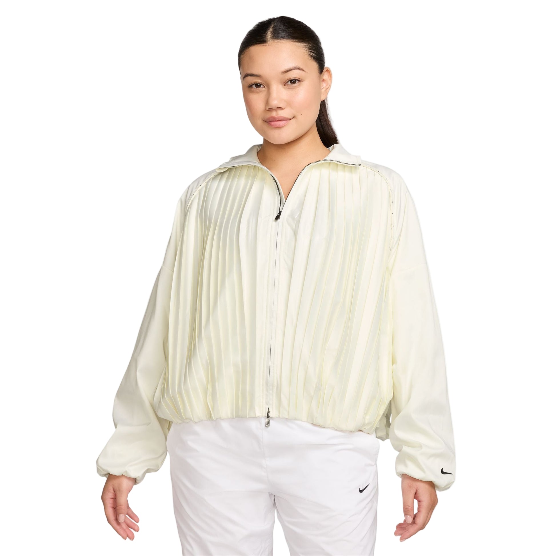 Woman wearing a light-colored pleated golf jacket and white pants on a white background