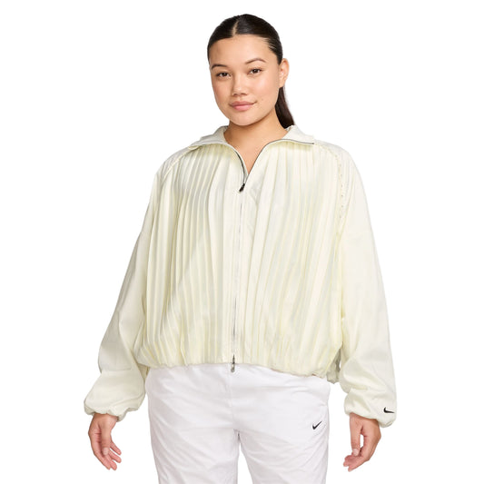 Woman wearing a light-colored pleated golf jacket and white pants on a white background