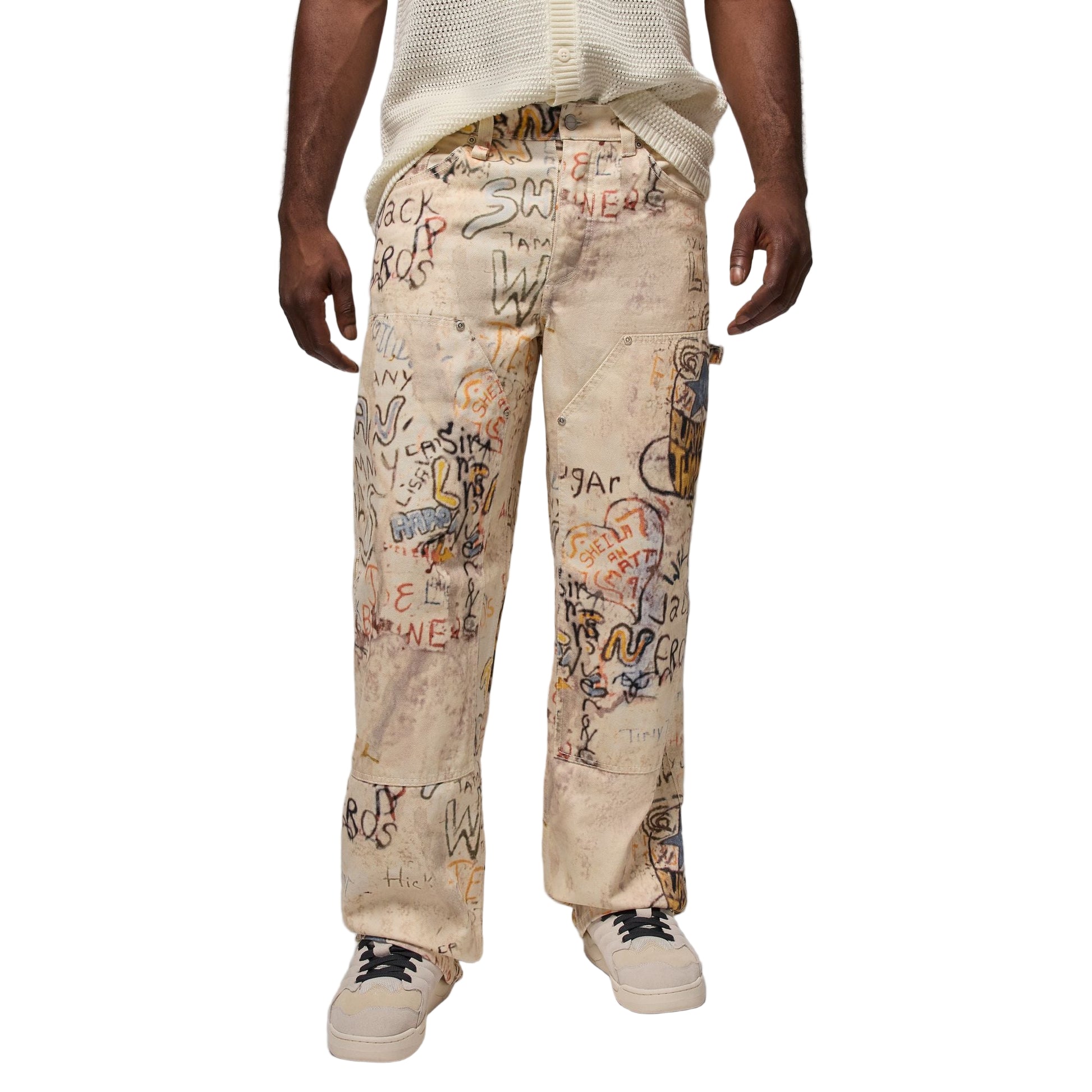 Beige pants with colorful text and graphics worn by a person on a white background