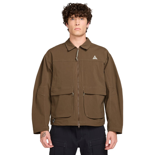 Man wearing a brown jacket with a Nike ACG logo on a white background