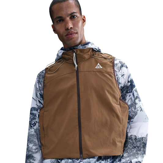 Man wearing a brown vest over a patterned shirt on a white background