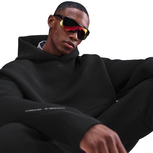 Person wearing a black hoodie and reflective sunglasses on a white background