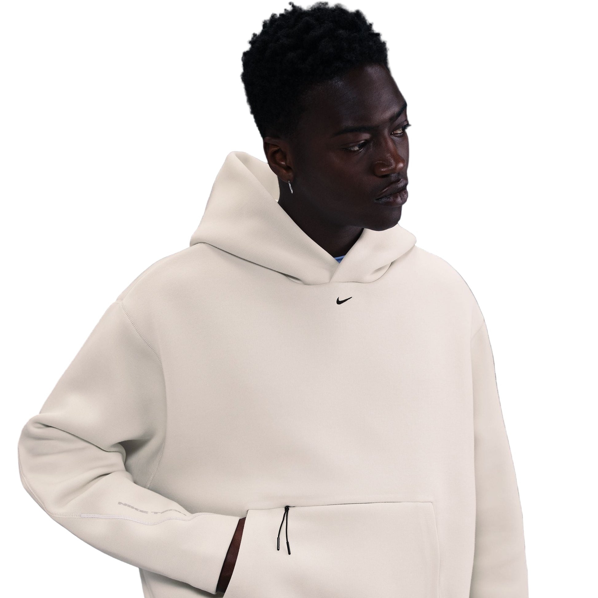 Person wearing a beige hoodie with a Nike logo on a dark background