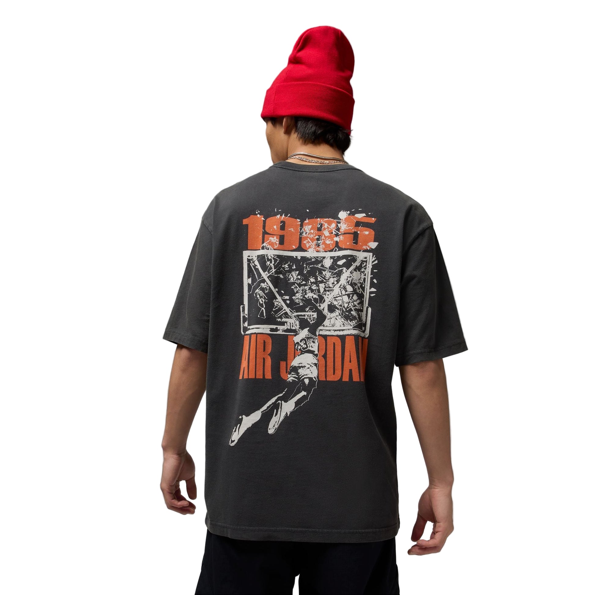 Person wearing a black t-shirt with '1985 Air Jordan' design and a red beanie on a gray background