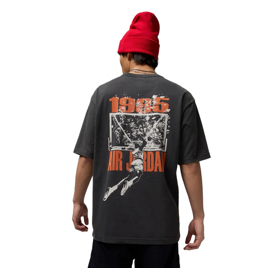 Person wearing a black t-shirt with '1985 Air Jordan' design and a red beanie on a gray background