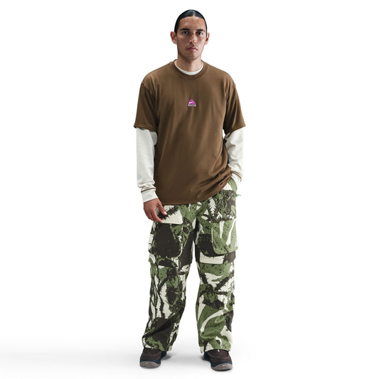Man wearing a brown shirt and camouflage pants on a white background