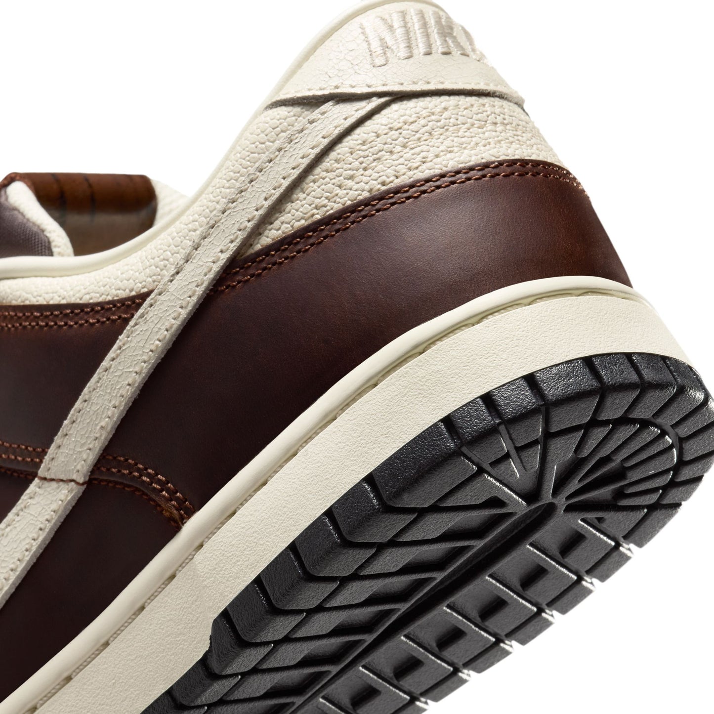 Close-up of a brown and beige Nike Dunk with 'Nike' branding on a white background