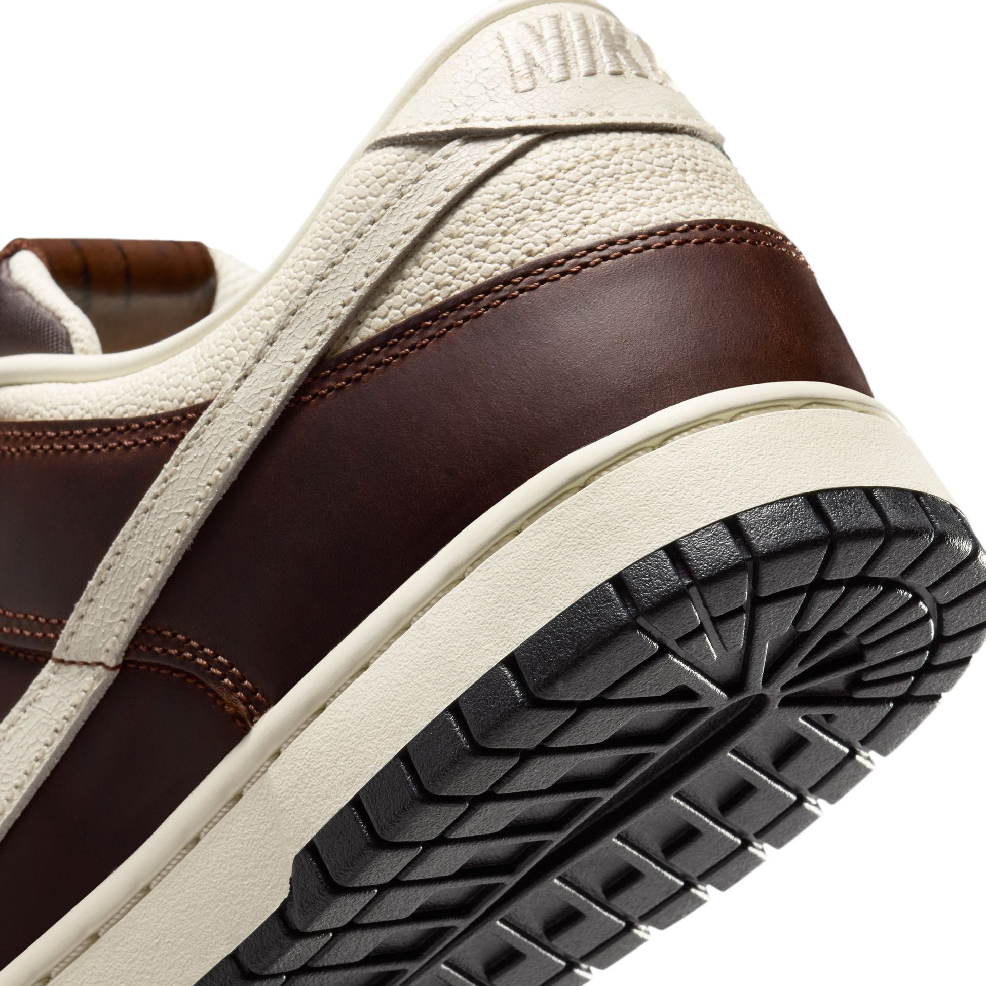 Close-up of a brown and beige Nike Dunk with 'Nike' branding on a white background