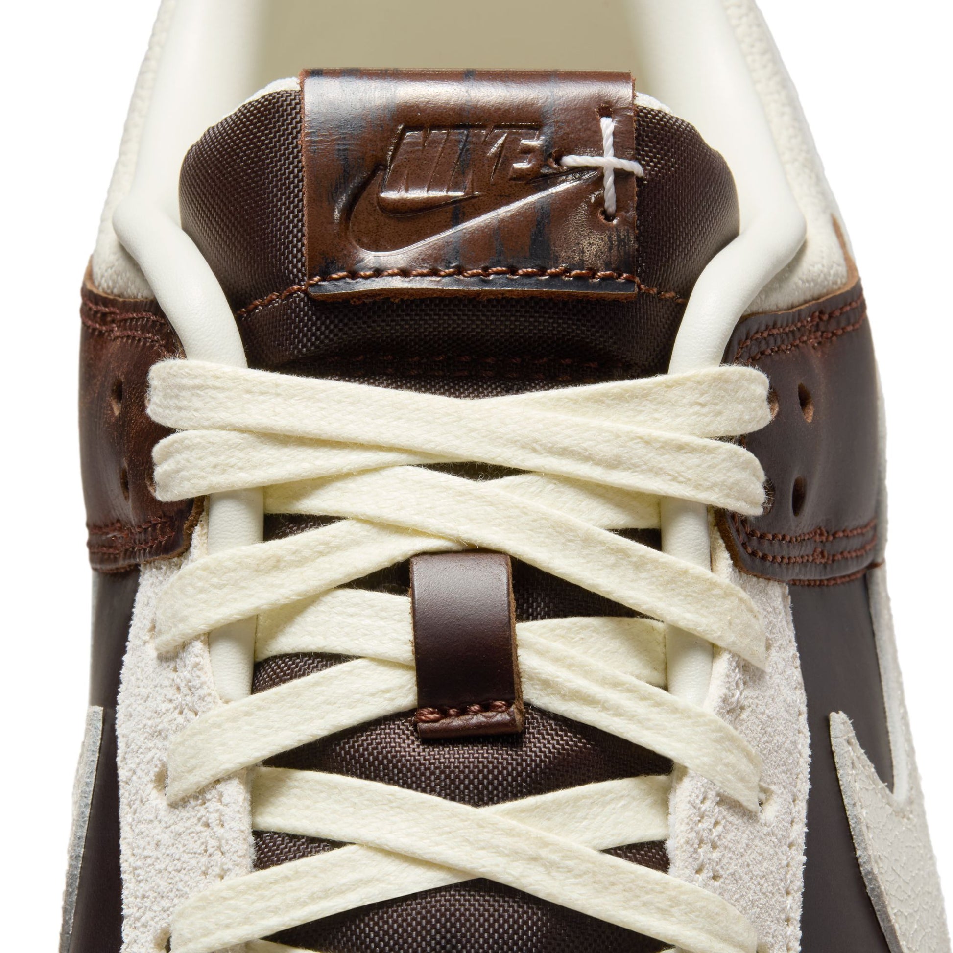 Close-up of a brown and white sneaker with laces on a white background