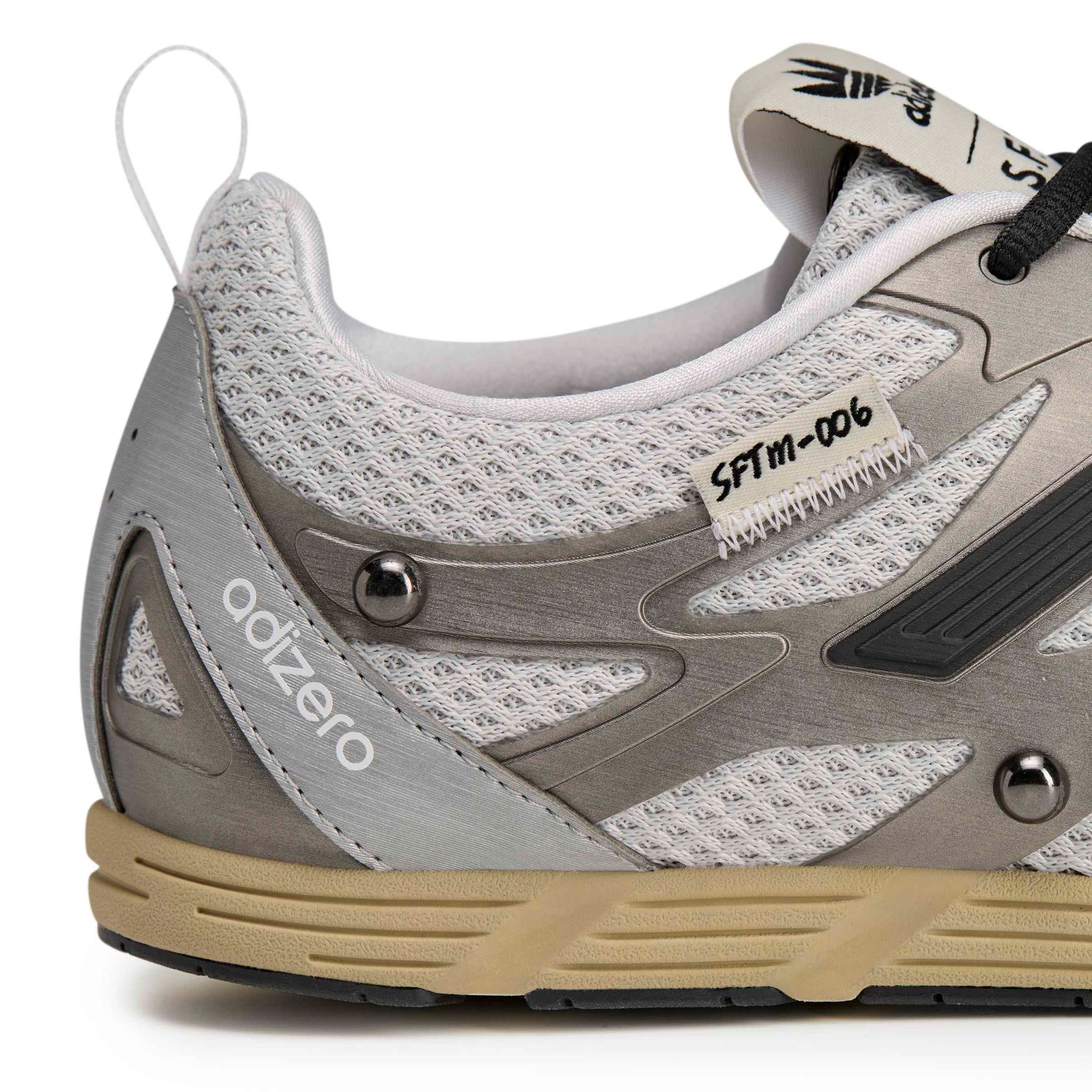 Gray and beige athletic shoe with 'adizero' branding on a white background