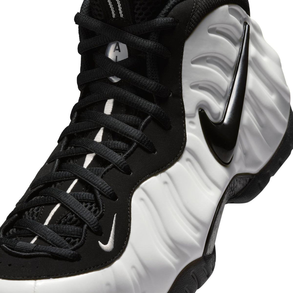 Nike Air Foamposite Pro close-up of Summit White molded shell, black Swoosh, black laces and nubuck upper
